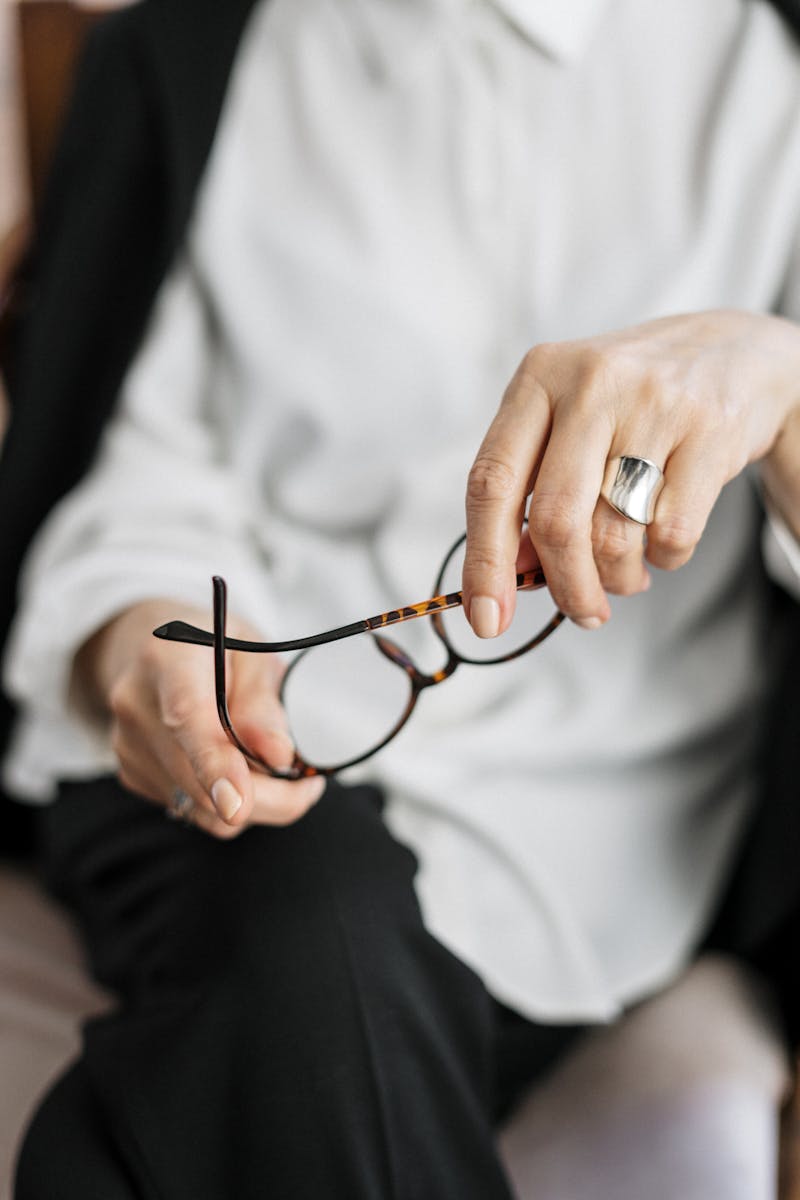 Close-up of a woman holding glasses, symbolizing thought and professionalism.